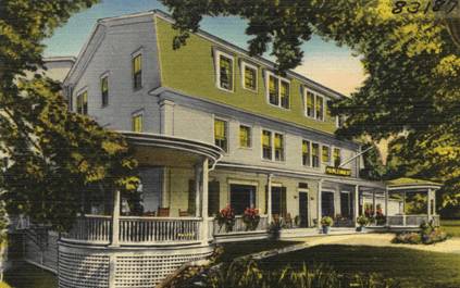A vintage illustration of a three-story hotel with a wraparound porch, green shutters, and potted plants. The building is surrounded by trees and bathed in warm sunlight.